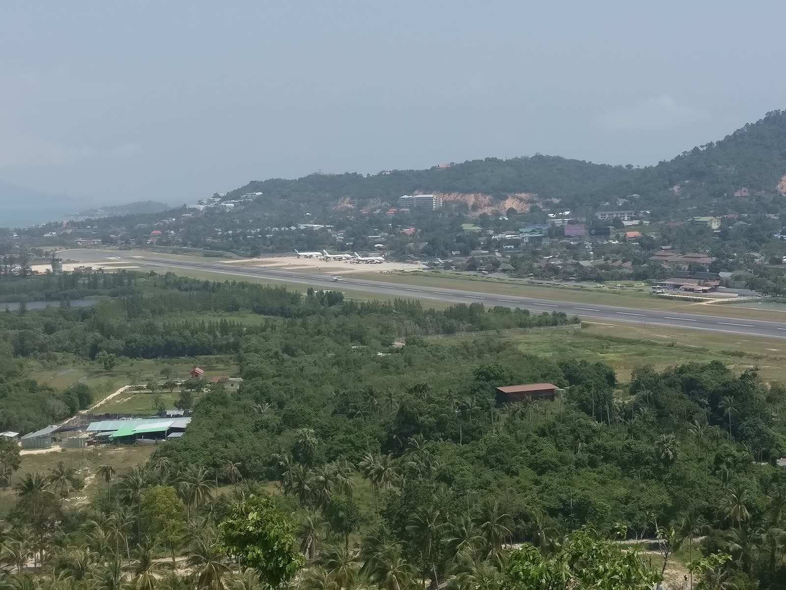 Samui International Airport from the hillside, showing the runway, parked aircraft and the terminal, Koh Samui