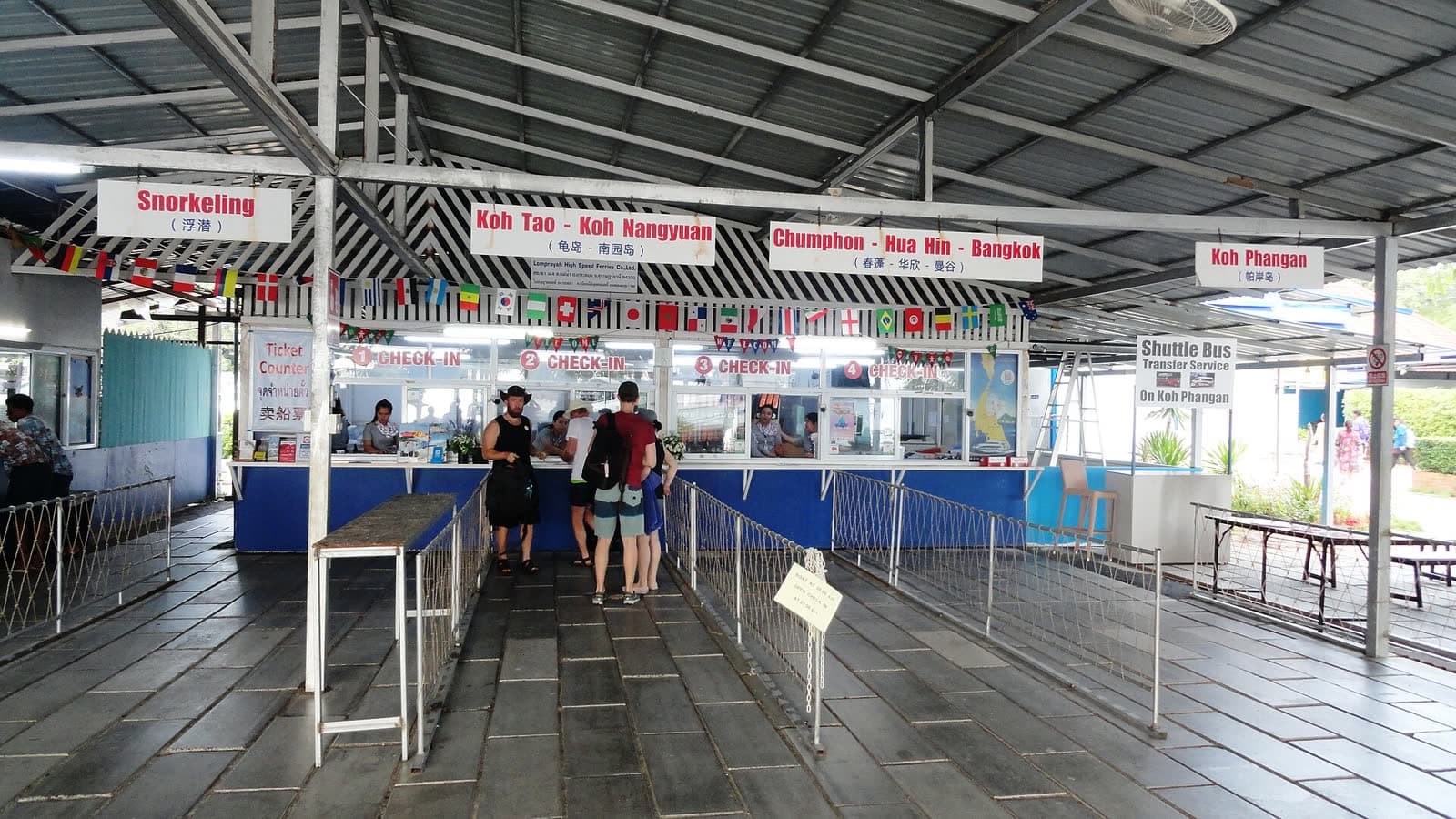 Ferry ticket counters at a Koh Samui pier, with departure boards for Koh Tao, Koh Phangan and the mainland